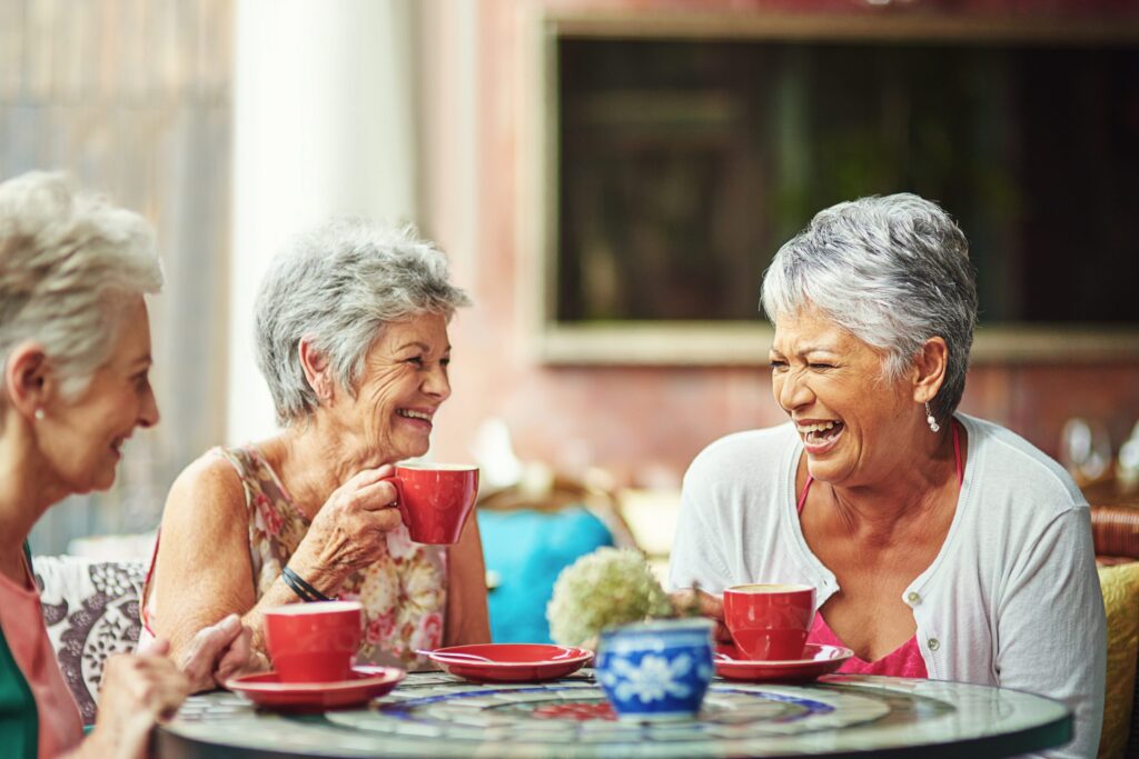 three women drinking tea and laughing together
